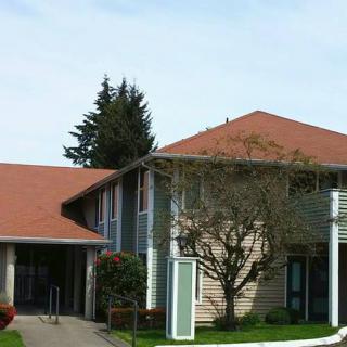 A suburban residential house with a red roof and surrounding greenery.