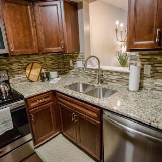 A modern kitchen featuring elegant wooden cabinets and a stylish granite countertop, complemented by stainless steel appliances.