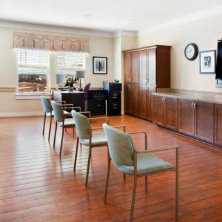 A spacious room with a wooden floor, featuring several chairs and office furniture.