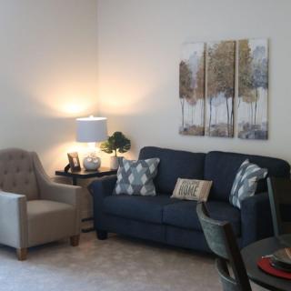 A cozy living room with a blue sofa, armchair, and soft lighting.