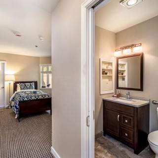 A modern bedroom with an adjoining bathroom, featuring elegant decor and furnishings.