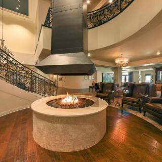 A modern lobby with a central fireplace and seating area.