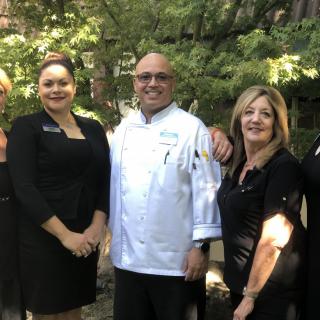 A group of people posing outdoors, including a chef in uniform.