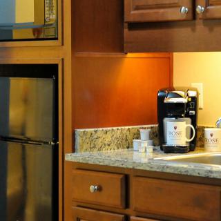 A kitchen counter with a coffee maker and mugs beside wooden cabinets.