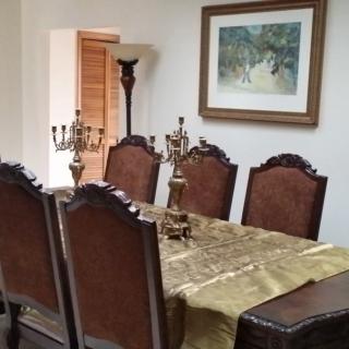 Elegant dining room with a table set for six, adorned with candelabras and artwork on the wall.