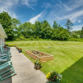 A spacious backyard with a well-maintained lawn, raised garden bed, and patio seating under a clear blue sky.