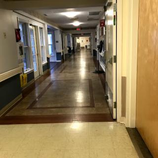 An empty hallway in a healthcare facility, showcasing well-lit interiors and doors along the corridor.