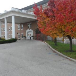 A building entrance with autumn trees displaying vibrant red leaves.