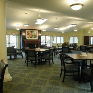 A spacious dining area with multiple tables and chairs under warm lighting.