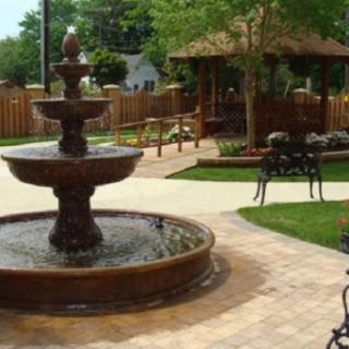 A tranquil garden with a multi-tiered fountain and a gazebo.