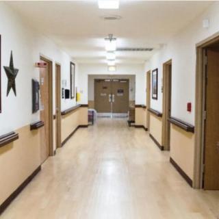 A clean and well-lit hospital hallway with doors on either side.