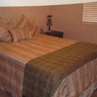 A cozy bedroom with a neatly made bed adorned with pillows and a throw blanket, showcasing warm brown tones in the decor.