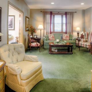 A cozy and classic living room with comfortable seating, a carpeted floor, and warm lighting.