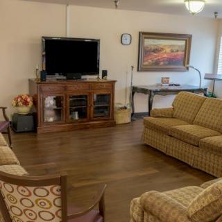 A cozy living room with a television, sofas, and artwork on the walls.