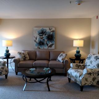A cozy living room with a sofa, two armchairs, lamps, and a decorative coffee table.