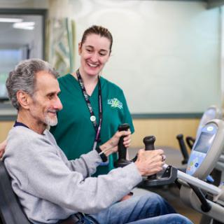A caregiver assists an elderly man with his exercise routine, promoting rehabilitation and wellness.