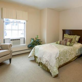 A cozy bedroom with a single bed and armchair by the window.