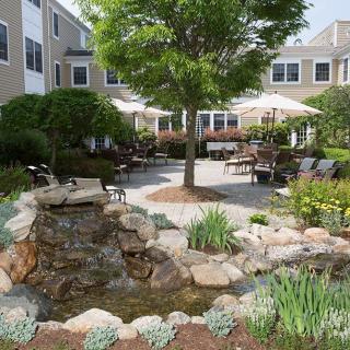 A peaceful courtyard garden with a water feature and seating areas surrounded by greenery.