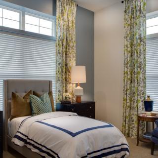 A cozy bedroom with a single bed, stylish lamp, and elegant curtains.