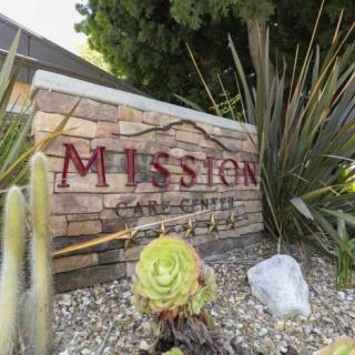 A decorative garden sign with succulents and a stone wall background.