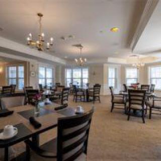 A spacious dining area with neatly arranged tables and chairs, illuminated by elegant chandeliers.
