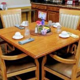 A dining table set for four with neatly arranged tableware and a centerpiece inside a room.