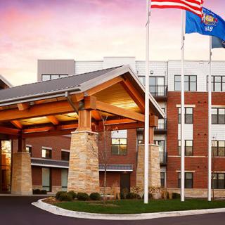 A modern hotel entrance with flags and a sunset backdrop.