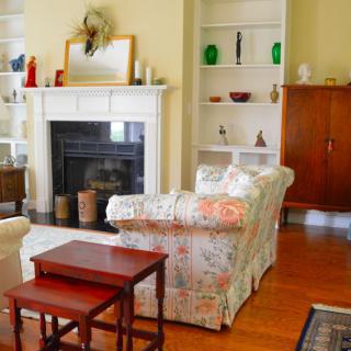 Cozy living room with a fireplace, patterned sofa, and decorative shelves.