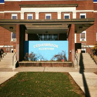 Entrance of a brick building with a prominent blue sign and stairs leading up.