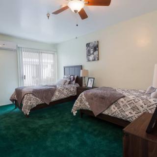A cozy bedroom with twin beds, a ceiling fan, and green carpet.