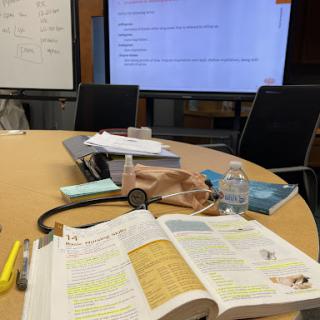 A study session in a meeting room with books, notes, and a computer display.