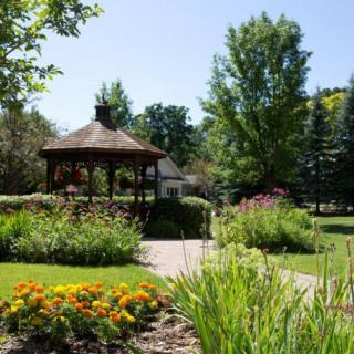 A serene park with a gazebo surrounded by lush greenery and colorful flowers.