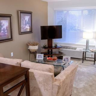 A cozy living room with a modern setup including a television, paintings on the wall, and comfortable seating.