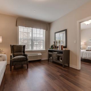 A cozy bedroom with elegant furniture and a large window, featuring hardwood flooring.