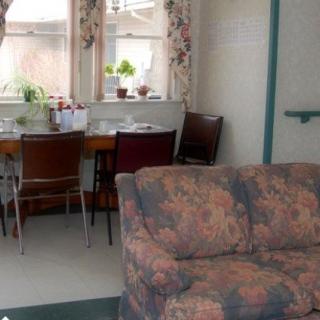 A cozy living room with a floral sofa and a dining area by the window.