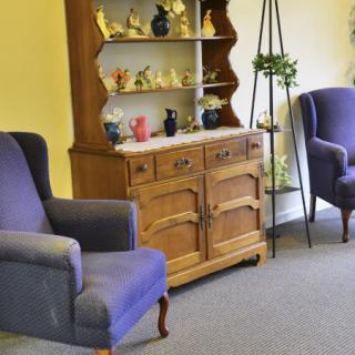 A cozy living room with vintage wooden cabinet and comfortable armchairs.