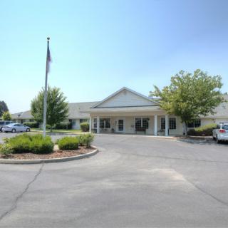 A building with a large entrance, surrounded by a parking lot and trees.