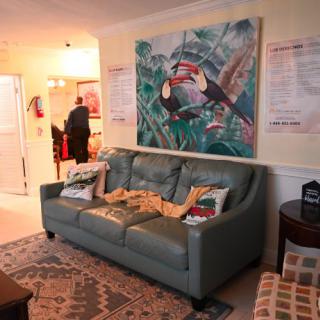 A cozy living room featuring a teal sofa adorned with cushions and an abstract painting hanging on the wall.