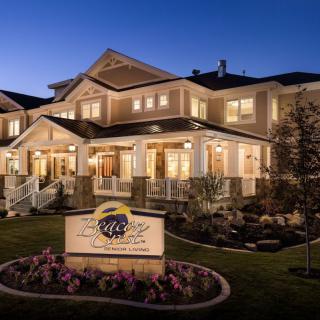 A well-lit residential building at night with a porch and landscaped garden.