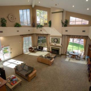 Spacious living room with high ceilings, large windows, and cozy furnishings.