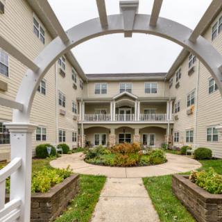 A view of a residential apartment building with a central courtyard garden, framed by an archway.
