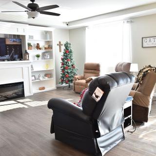 A cozy living room featuring a fireplace, recliners, and a decorated Christmas tree.