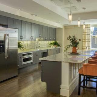 A modern kitchen featuring stainless steel appliances and a spacious island with pendant lighting.