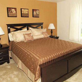 A cozy bedroom with a large bed, bedside tables and lamps, and artwork on the walls.