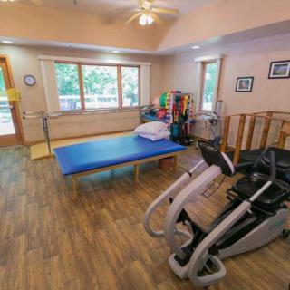 A physical therapy room equipped with exercise machines and a treatment table.