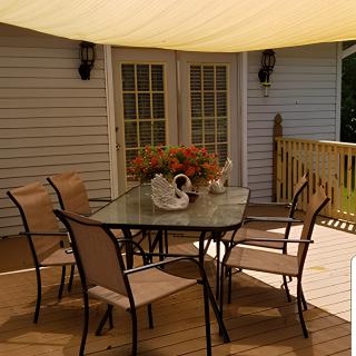 A cozy outdoor patio setup with a table and chairs under a shade sail.