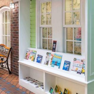 A charming storefront display with books arranged on a white shelf against a backdrop of windows and brickwork.
