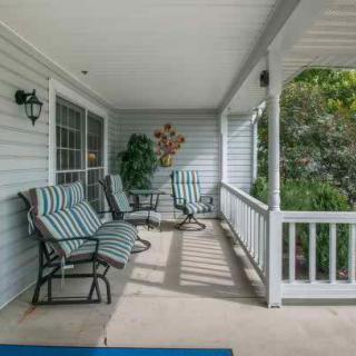 A cozy covered porch with comfortable seating and a small table.