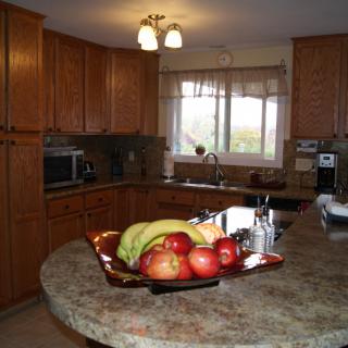 A cozy kitchen with wooden cabinets, featuring a countertop adorned with a fruit bowl containing apples and bananas.