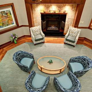 A cozy living room features a circular seating arrangement around a central table, complemented by a warm, inviting fireplace.